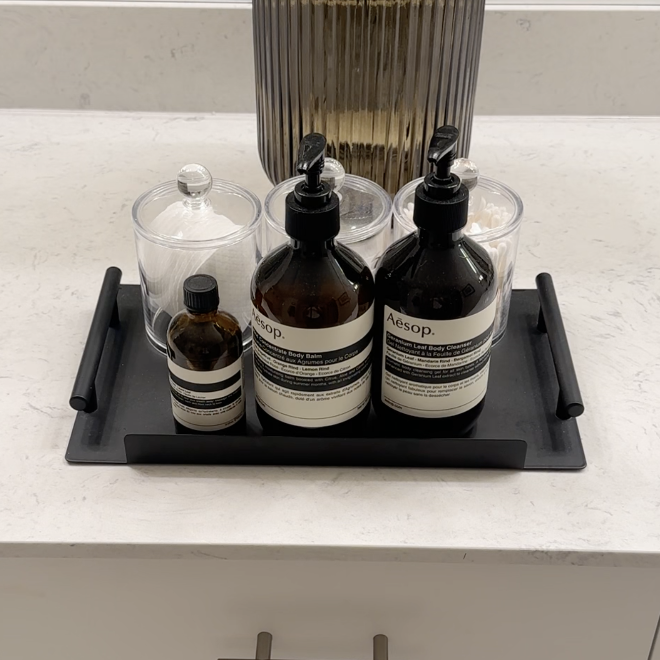 A bathroom tray with assorted toiletries nearly organized on the countertop