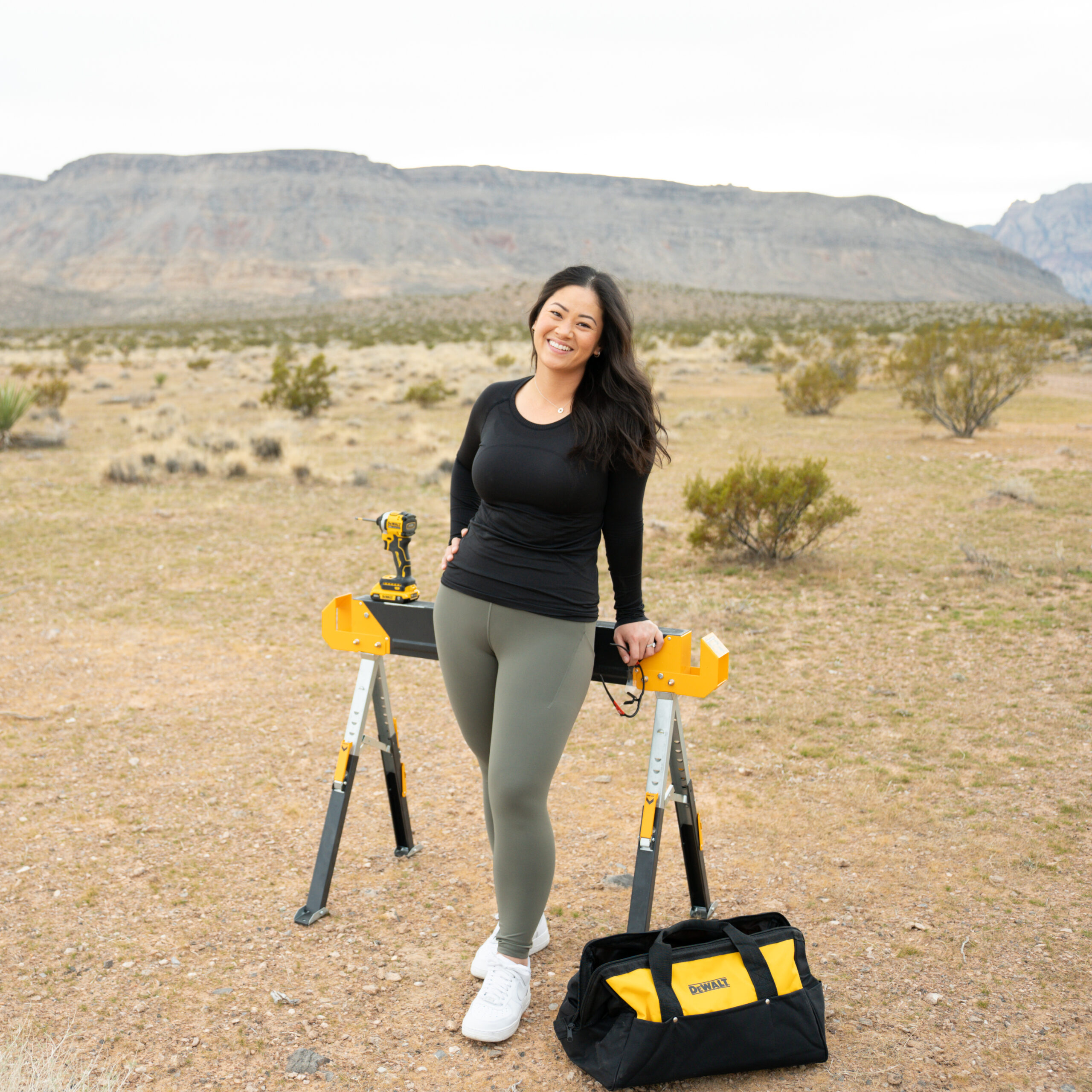 Deedee Oguma leaning on a sawhorse with her DeWalt tools at Red Rock National Park