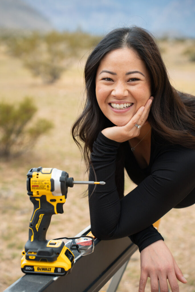 Deedee Oguma leaning over a sawhorse with her driver drill and safety glasses at Red Rock National Park